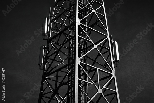Black and white image of a cellular tower with a geometric metal structure.