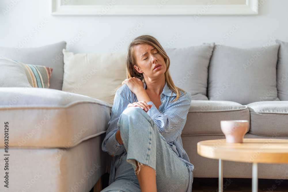 Young Woman Sitting on Floor Feeling Discomfort in Relaxed Home Setting Young Woman Sitting on Floor Feeling Discomfort in Relaxed Home Setting