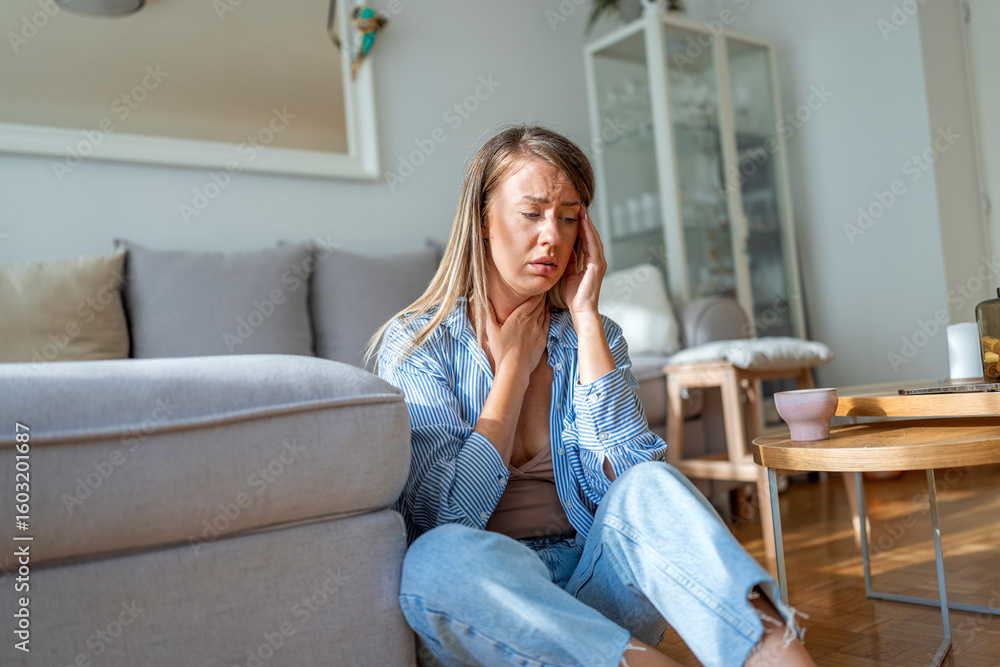 Young Woman Sitting on Floor Feeling Unwell and Holding Her Head Young Woman Sitting on Floor Feeling Unwell and Holding Her Head