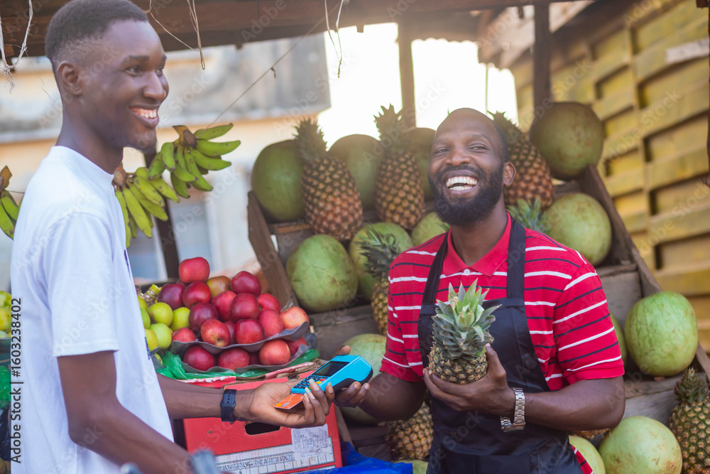 Fototapeta premium close up of black man selling fruit in a local african market to a male customer smiling and feeling happy and satisfied