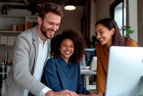 3 coworkers in a work meeting looking at a computer monitor
