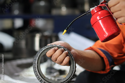 Close up male hand lubricating bearings with oil can. Industrial concept.