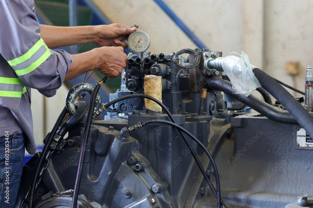 Fototapeta premium mechanic is checking and inspecting the Komatsu D155 transmission trouble while testing the transmission on the test bench in the workshop.