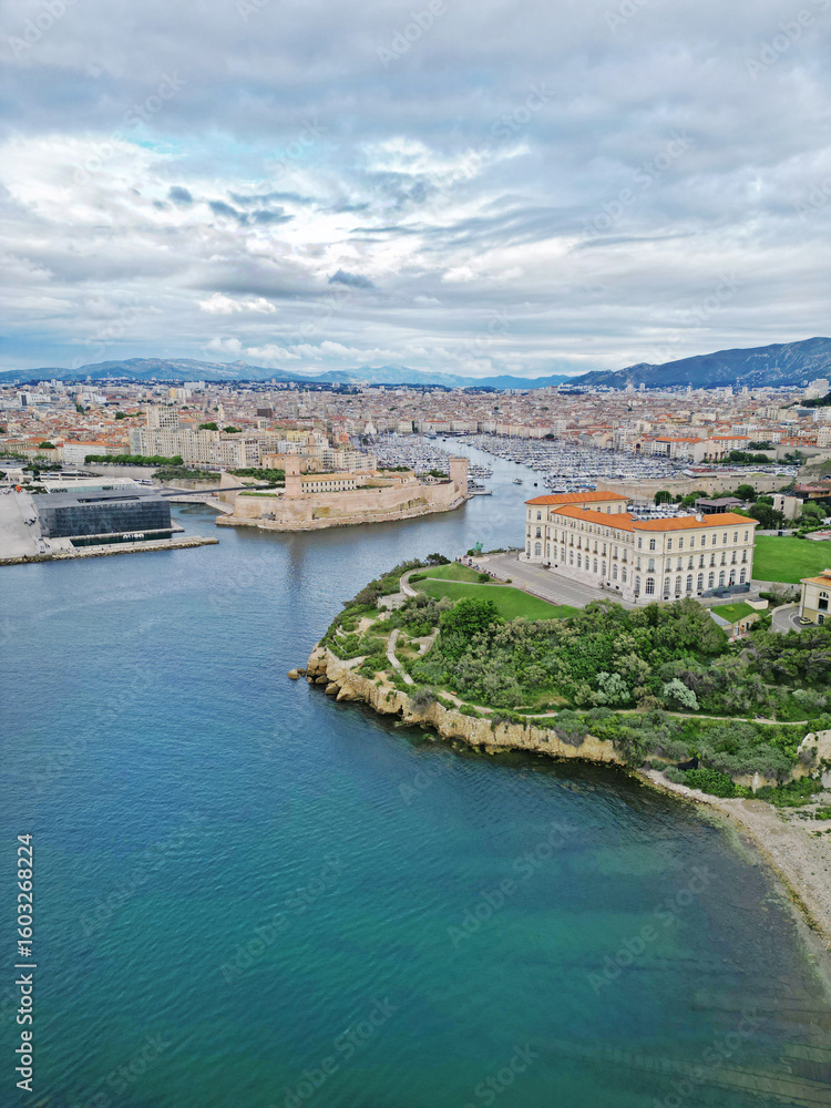 Fototapeta premium Aerial view of a coastal cityscape featuring a historic fort, modern buildings, and lush greenery along the waterfront, showcasing the beauty of urban architecture and nature