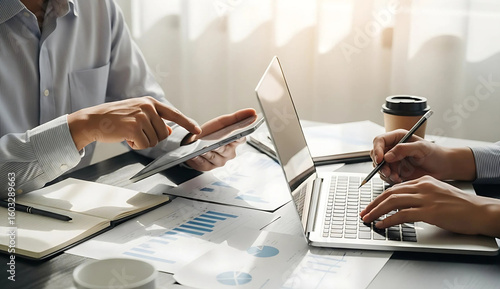 Businessman analyzing financial data with laptop and tablet for strategic planning and investment decisions in a corporate office setting