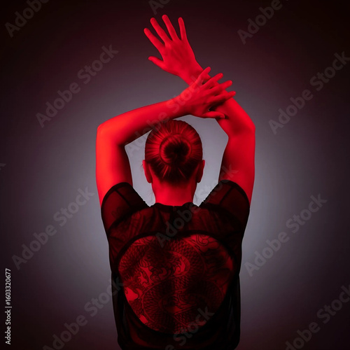 Woman in dance pose illuminated by red light creating dramatic art