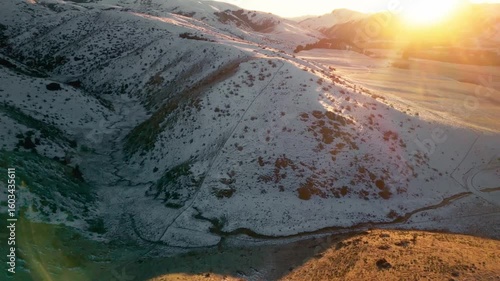 Drone push in video of a sunrise over snowy hills