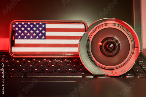 Camera lens and cell phone with American flag sitting on a computer