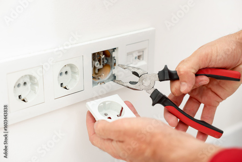 Schilderij op canvas Man fixing power sockets with pliers indoors, closeup