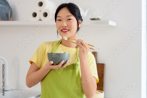 Young Asian woman eating ta...