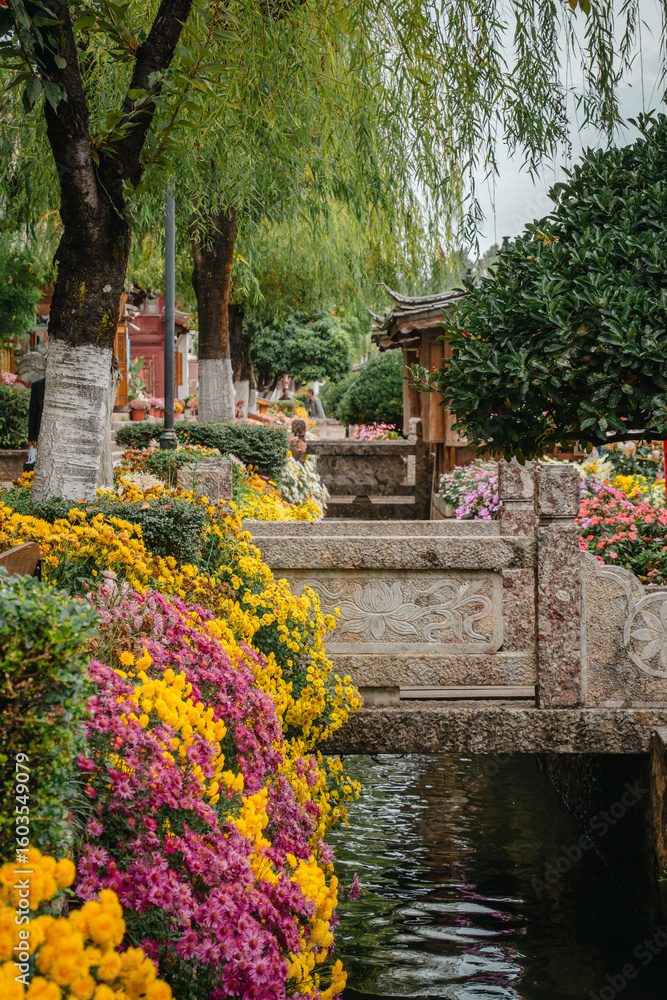 Obraz premium Stone bridge over flower-lined canal in Lijiang Old Town, China