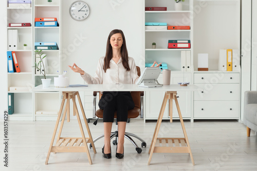 Young businesswoman meditat...