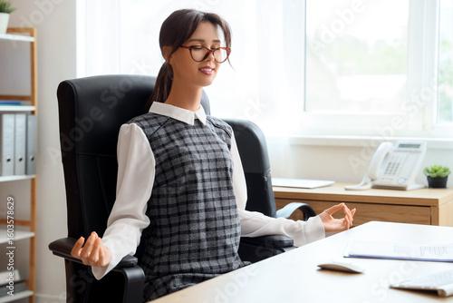 Young businesswoman meditating at table in office