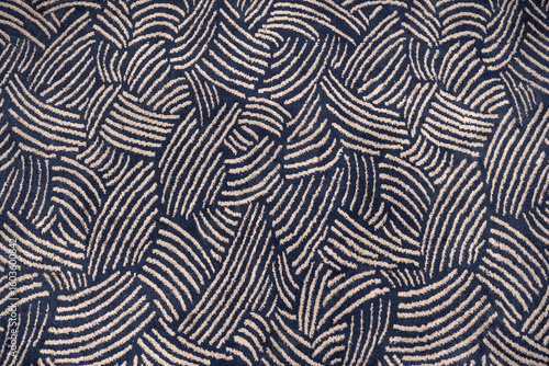 Abstract seamless pattern of a dark blue and beige carpet texture. Top-down view of woven fabric with curved lines, suitable as a background.
