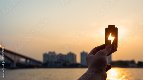 People in a common household holding a symbol of electricity to shine at the sun. The concept of household energy usage tends to increase along with the price and cost of electricity production.