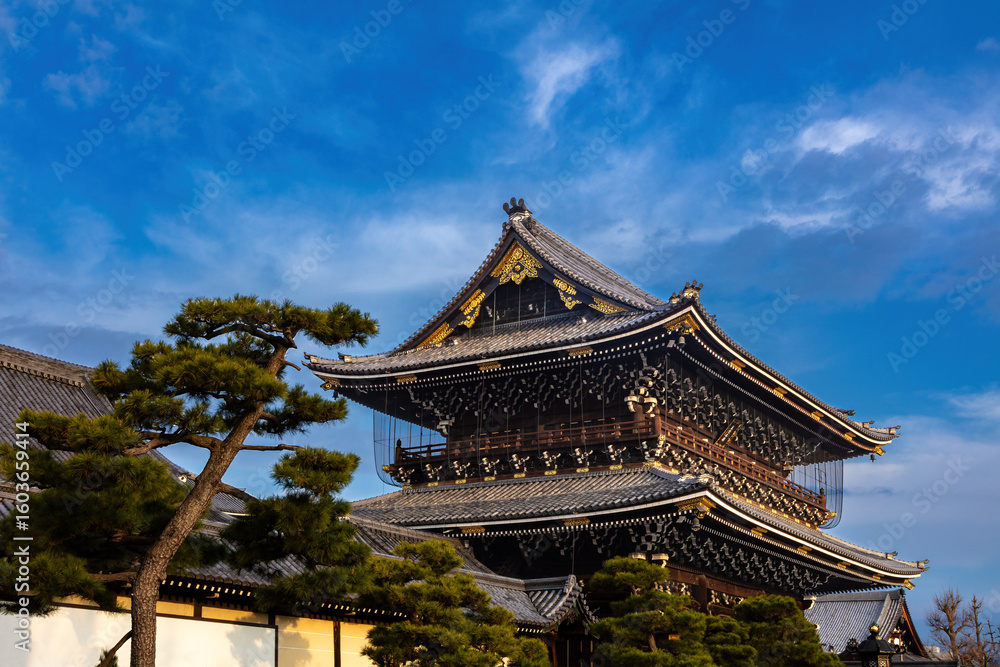 Obraz premium Main hall, Hongan-ji temple in Kyoto, Japan. Gravel yard in foreground. Blue sky, clouds overhead. 