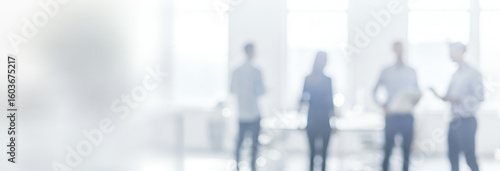 Blurred group of people standing in a bright office space.