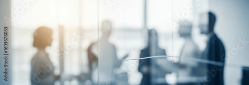Blurred group of people in an office setting with bright light.