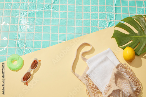 Gentle summer poolside with yellow tiles, green float, sunglasses, and a woven bag beside clear turquoise water, leaving a soft open space for creative designs.