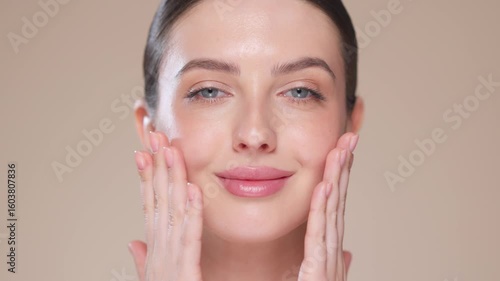 Beautiful Young Woman Touches Her Perfect Face. Natural Cosmetic Skincare Products. Woman demonstrate moisturizing facial care. Elevating Close-up Portrait with Isolated Background