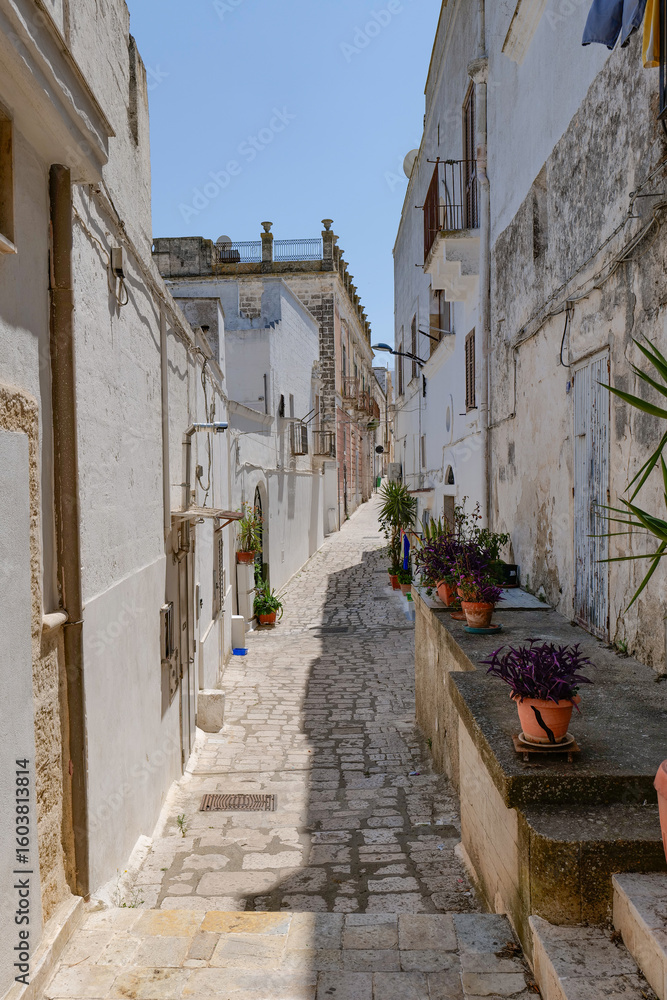 Obraz premium A narrow street among the white houses of Ginosa, an Apulian village, Italy.