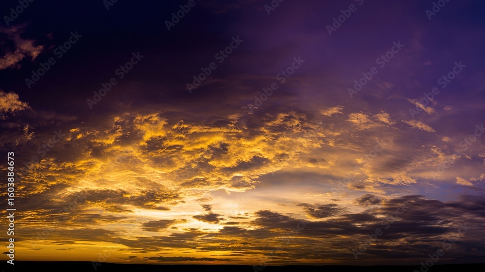 Fototapeta premium Dramatic sunrise with gradient orange and purple clouds, creating a panoramic abstract sky view.
