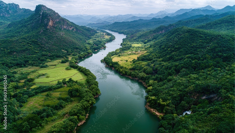 Fototapeta premium Aerial view of a winding river flowing through lush green valleys and mountains