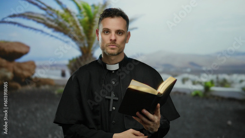 Wallpaper Mural Man in clerical black robe holding open book stands by beachside promenade with palm trees and ocean view under clear sky suggesting reflective moment Torontodigital.ca