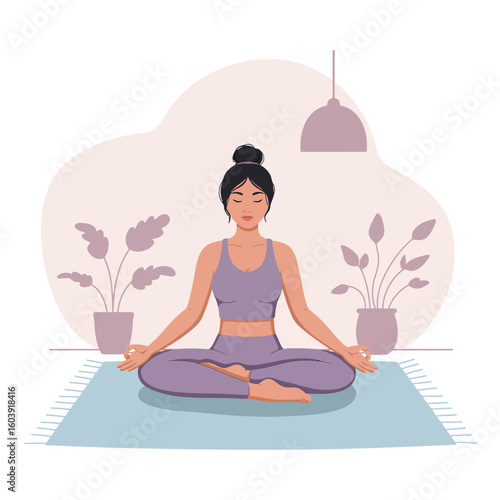 A serene woman with dark hair sits in a peaceful lotus yoga pose on a blue mat, practicing mindfulness and meditation indoors.
