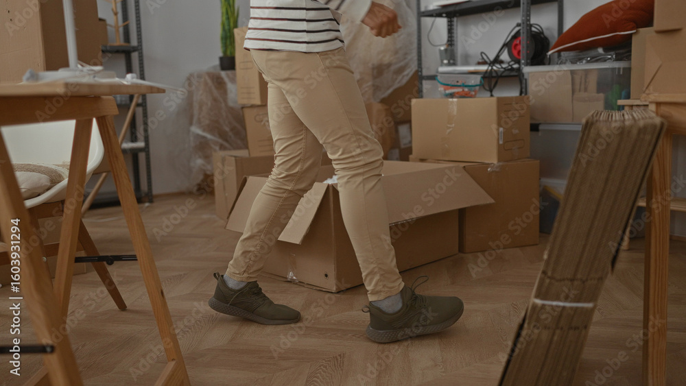 Fototapeta premium Hispanic man organizing boxes in a new home interior with visible furniture and accessories suggesting moving activities and unpacking in the living room.