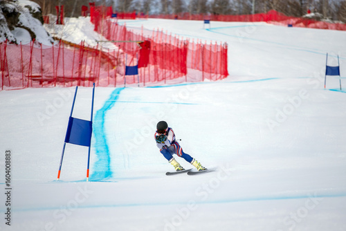 alpine skier racing downhill on snowy ski slope during giant slalom competition
