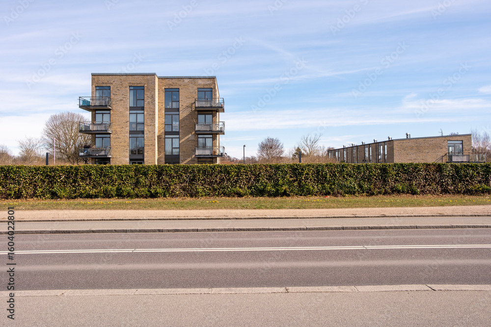 Modern low-rise building facing urban greenery with open sky, designed with symmetry and rhythm in mind, suitable as neutral background or for real estate and lifestyle themes Modern low-rise building facing urban greenery with open sky, designed with symmetry and rhythm in mind, suitable as neutral background or for real estate and lifestyle themes
