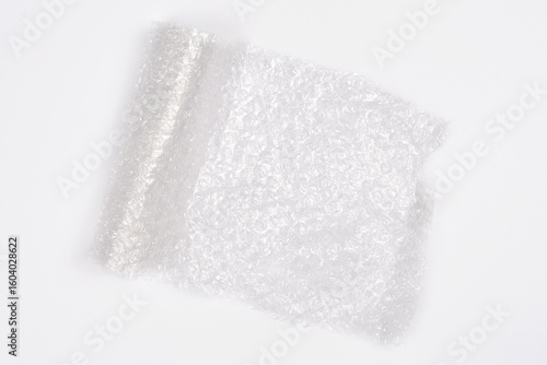 An overhead shot displays a partially unrolled section of clear bubble wrap on a plain white background, highlighting its crinkled texture