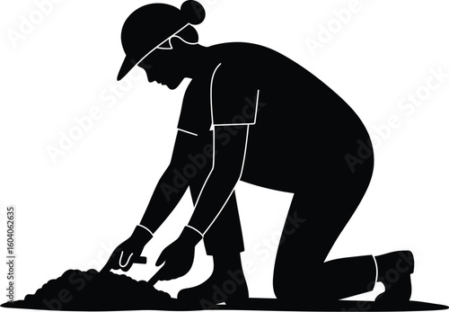 Silhouette of a woman gardening kneeling and using a trowel in the soil