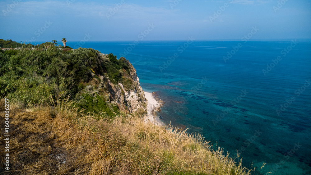 Fototapeta premium Cliffside Vegetation and Turquoise Waters – Aerial View of Mediterranean Coastline in Calabria, Italy