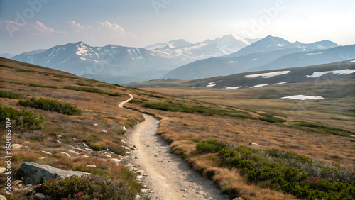 Winding Trail Amidst Mountain Majesty: A scenic pathway carves its way through a vast, open landscape, guiding the viewer's eye towards majestic snow-capped peaks.