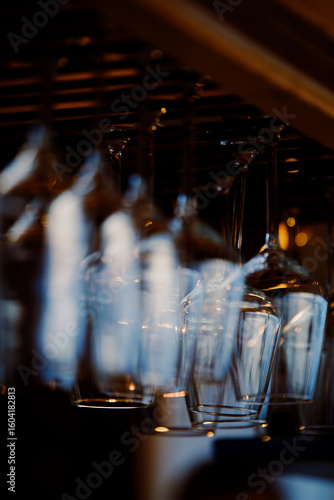 Glass goblets suspended above a bar counter. Summer evening. Light reflections