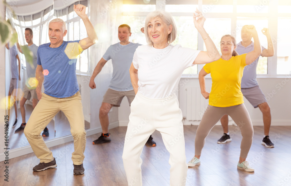 Naklejka premium Elderly woman rehearsing modern dance in group in dance studio