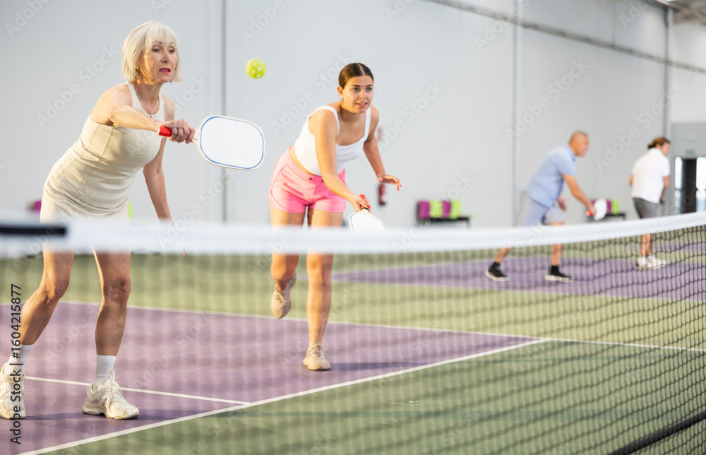 Obraz premium Athletic womens playing pickleball tennis on the pickleball court indoors