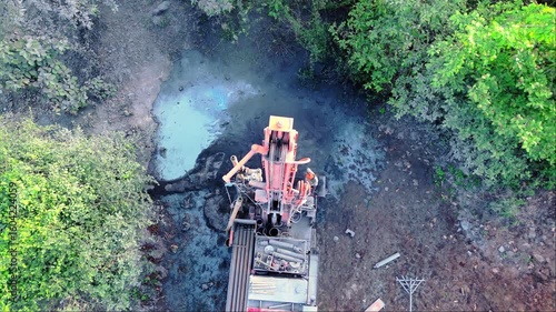 Drone shot borewell drilling amid forest canopy