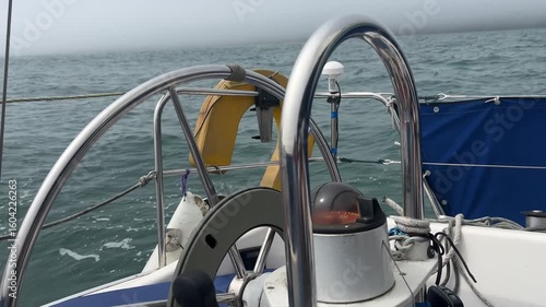 A sailing boat autopilot steering a yacht sailing downwind in light airs. The motor inside the wheel turns the wheel to keep the sailing vessel on its designated course.