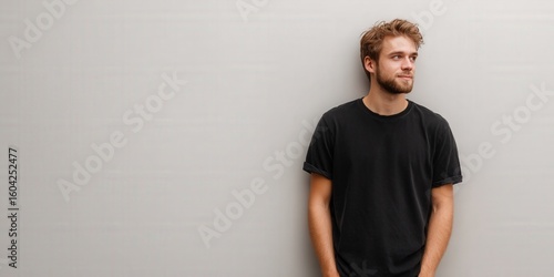 Casual Young Man Leaning Against a Wall, Exuding Confidence and Relaxation