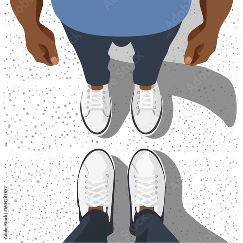 Overhead view of two pairs of legs and feet wearing casual shoes standing on an urban patterned surface.