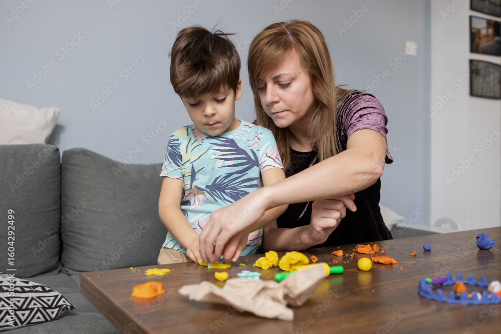 Naklejka premium Mother and son playing with modeling clay at home