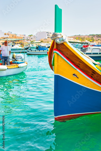 Malta Republic, Malta Island. 28. 06.2023. Marsaxlokk city, The harbour and traditional coloured boats on a hot sunny day. This town has a big market every weekend.