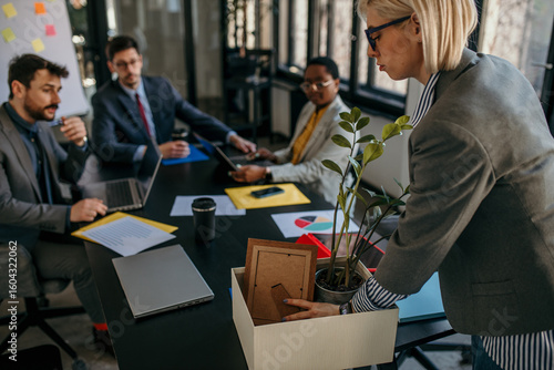 Businesswoman leaving job packing personal items after redundancy