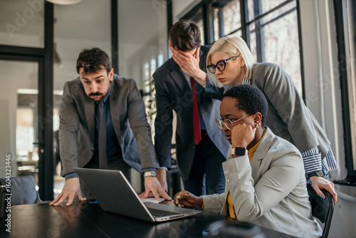 Business people reading shocking news on laptop in office meeting