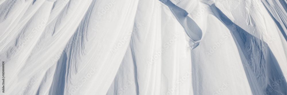 Obraz premium Snow texture. Wind sculpted patterns on snow surface. Wind in the tundra and in the mountains on the surface of the snow sculpts patterns and ridges. Arctic, Polar region. Winter panoramic background.