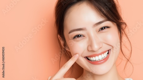 A woman with a bright smile is pointing at her teeth. Concept of confidence and positivity, as the woman is proud of her smile and is showing it off