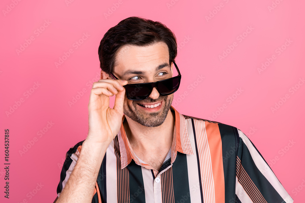 Obraz premium Trendy young man with sunglass smiling against a pink background showcasing casual fashion and lifestyle style